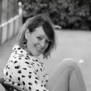 Lachende vrouw met kort haar en vlekjes blouse.