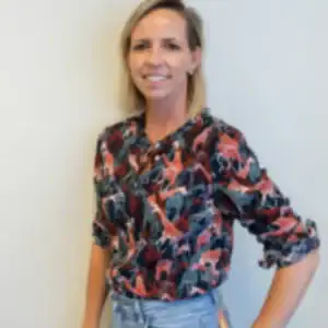 Blonde vrouw met kleurrijke blouse en jeans.