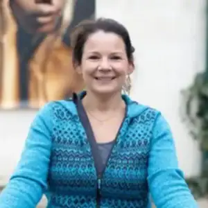 Geleide vrouw met blauwe jas glimlachend.