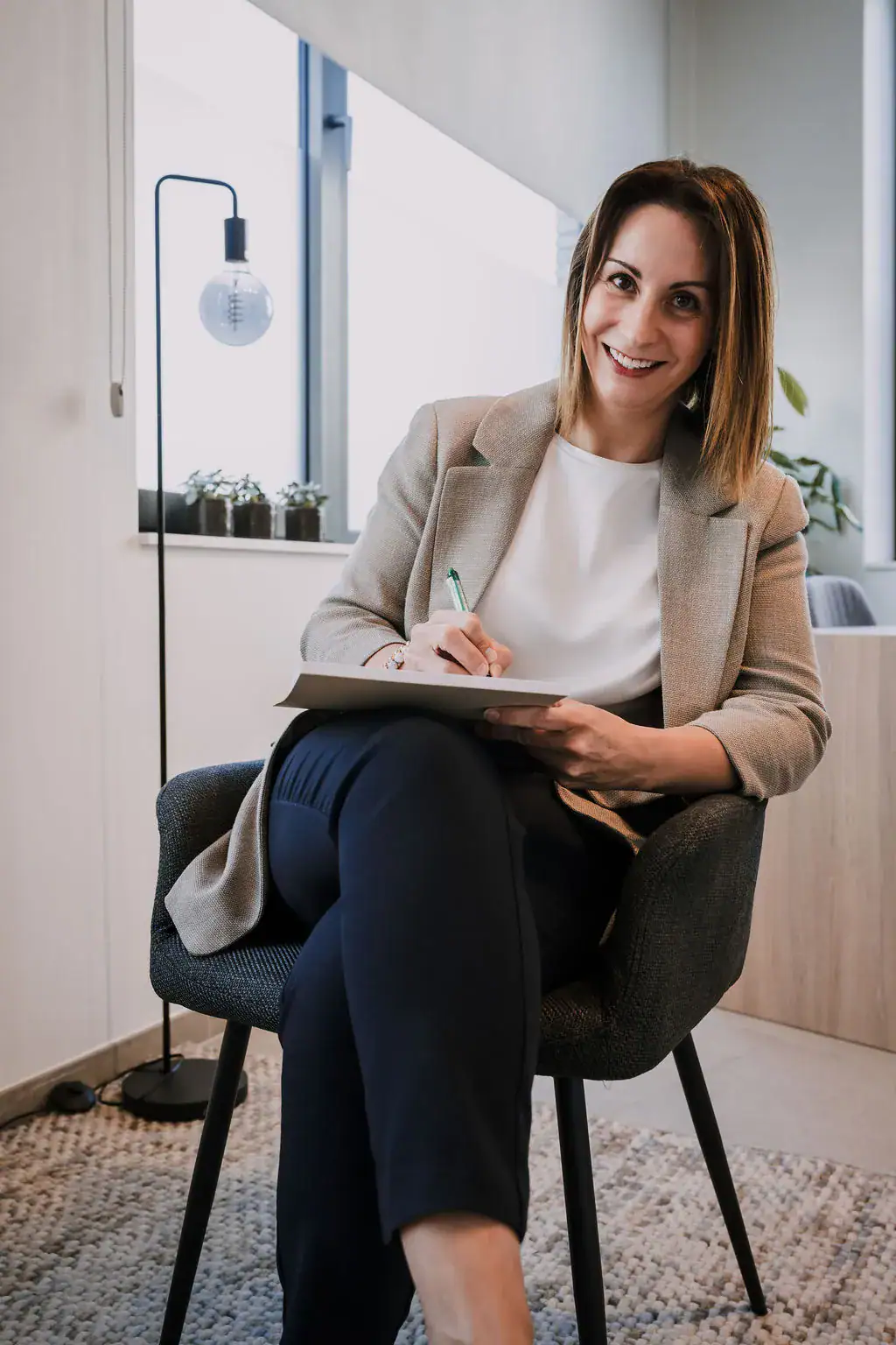 Gevrouwen die in een kantoor zit en een notitieboekje vast houdt.